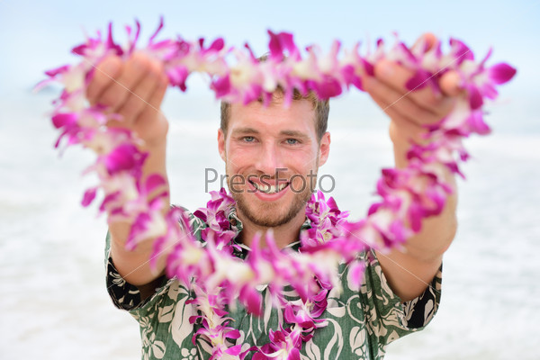 Hawaii Caucasian man with welcome Hawaiian lei. Male tourist portrait holding flower necklace giving it to the camera as a welcoming gesture for tourism in Hawaii. Travel vacation concept.