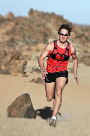 Runner. Man running fast in dramatic desert landscape. Fit fitness trail runner sprinting at high speed. Caucasian male model outside.