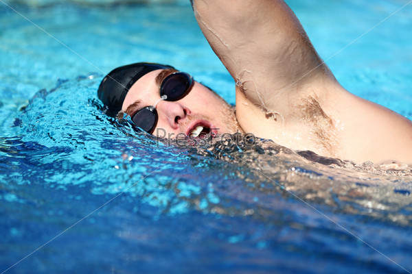 Man swimming crawl. Male freestyle swimmer crawling doing crawl-swimming stroke in pool wearing swimming goggles and swim cap. Caucasian male sport fitness model.