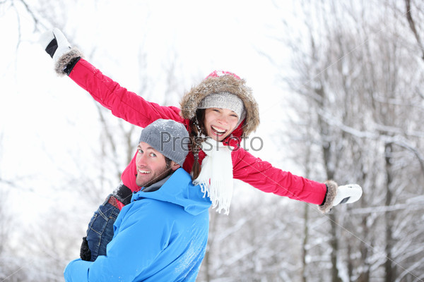 Winter fun couple playful together during winter holidays vacation outside in snow forest. Happy young interracial couple, Asian woman, Caucasian man.