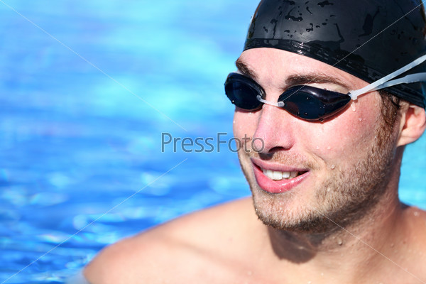 Male Swimmer Portrait. Man swimming model smiling happy wearing swimming goggles and swim cap in pool looking at copy space. Young caucasian male model.