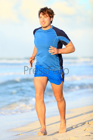 Running man. Male runner jogging on beach barefoot during outdoor sport fitness exercise. Caucasian male fitness model in his twenties
