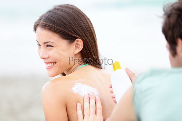 Suntan lotion /  Sunscreen - young multiethnic couple on beach