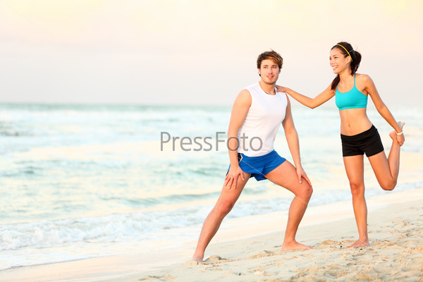 Couple doing stretching exercises workout training on beach. Young interracial running couple stretching after jogging outdoors on beautiful beach. Asian woman fitness model, Caucasian man.