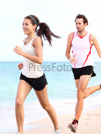 People running: couple runners training outdoors on beach. Young multiracial woman fitness model and caucasian man runner.