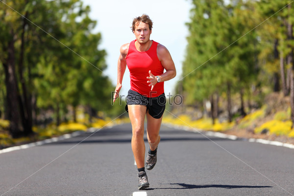 Running fitness sport man. Male runner sprinting on road - fit muscular male model training for marathon running fast on beautiful road in nature.
