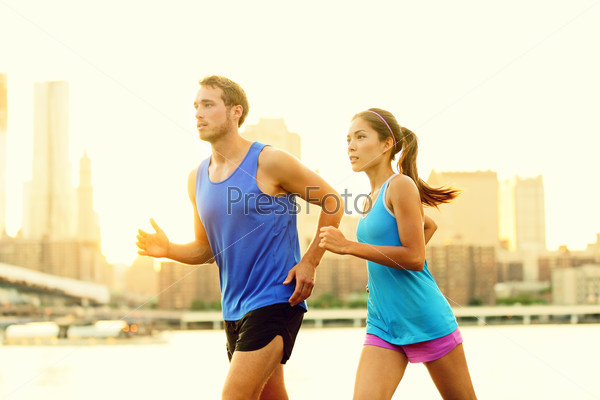 City Running Couple Jogging Outside. Runners Training Outdoors Working Out In Brooklyn With Manhattan, New York City In The Background. Fit Multiracial Fitness Couple, Asian Woman, Caucasian Man.