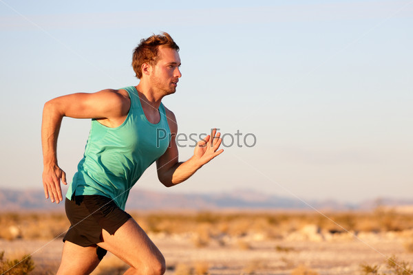 Running man sprinting cross country trail run. Male fit sport fitness model training for marathon outside in beautiful landscape. Caucasian handsome guy in his 20s.