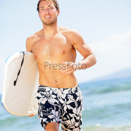 Handsome man surfer fun on summer beach. bodyboarding surfing good looking fit fitness model running with bodyboard surfboard during vacation holidays getaway. Caucasian male model in his 20s.