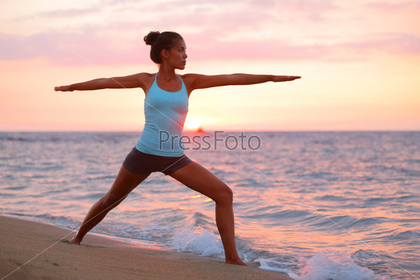 Yoga woman in meditating in warrior pose at beach