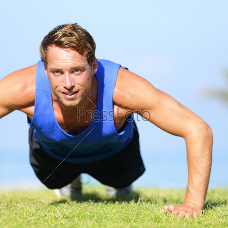 Push ups - fitness man exercising push up outside in grass in summer. Fit male athlete working out cross training outdoor. Caucasian muscular sports model in his 20s.