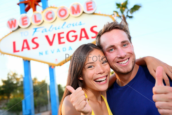 Las vegas couple happy and excited at welcome to fabulous Las Vegas sign billboard at the strip. Young multiracial people, Asian woman and Caucasian man having fun on travel in Las Vegas, Nevada, USA.