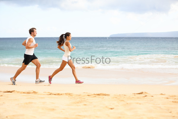 Running People - Woman And Man Athlete Runners Jogging In Sand On Beach. Fit Young Fitness Couple Exercising Healthy Lifestyle Outdoors. Male Athlete And Female Fitness Model Training Together.