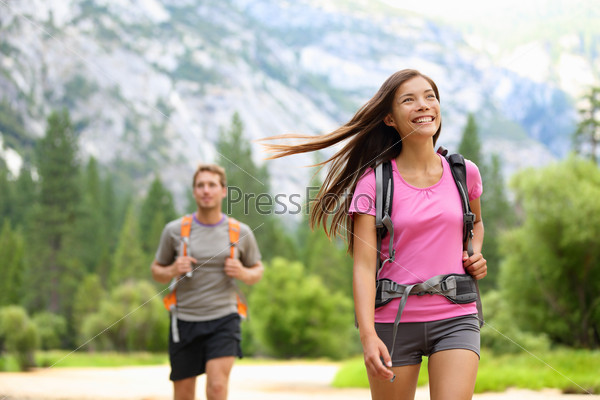 People hiking - happy hikers on hike trekking travel trek during summer vacations outdoors in beautiful forest mountain landscape in Yosemite national park, California, USA. Man and woman together.
