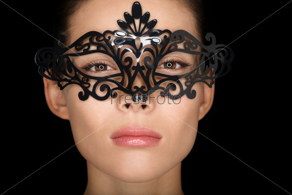 Mask. Beauty woman wearing carnival mask isolated on black background. Close up portrait of young mixed race Asian Caucasian girl hiding behind mask.
