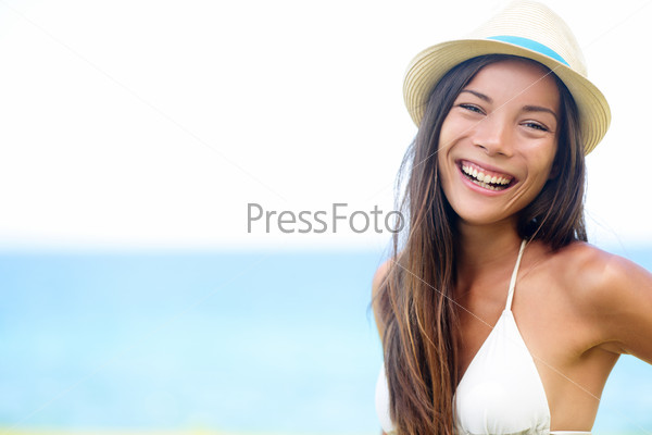 Woman - happy joyful beach summer girl portrait. Laughing lovely smiling multiracial young female model looking excited at camera wearing hipster hat by the ocean sea on sunny summer day by the water.