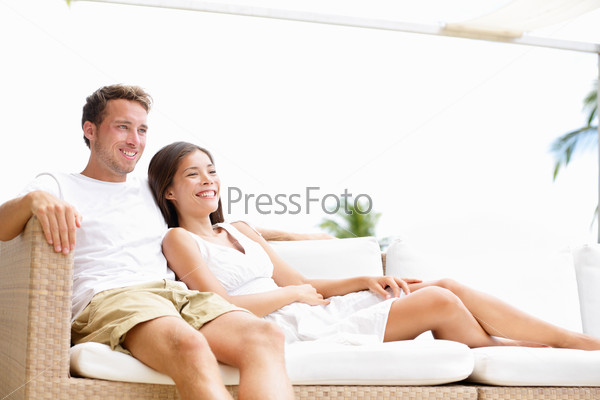 Couple relaxing together in sofa. Romantic young happy multi-ethnic couple lying at home in sofa resting having fun together maybe watching tv. Asian woman, Caucasian man.