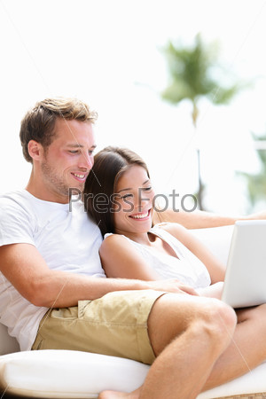 Couple relaxing together in sofa with laptop pc