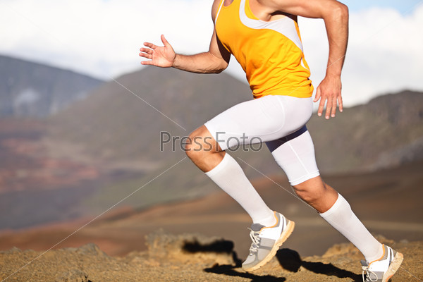 Running sport fitness man. Closeup of strong legs and shoes in action. Male athlete fitness runner sprinting fast outside in compression sports clothing, socks and tights shorts. Trail running concept