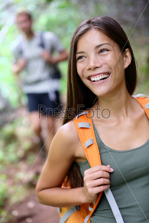 Hiking woman. Portrait of happy female hiker smiling looking away during hike trekking in forest wearing backpack. Asian girl in her twenties in Iao Valley State Park, Maui, Hawaii, USA.