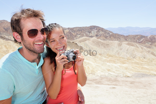 Tourists couple fun in Death Valley. Tourist woman and man taking pictures with camera enjoying the view and desert landscape of Zabriskie Point in Death Valley National Park, California, USA.
