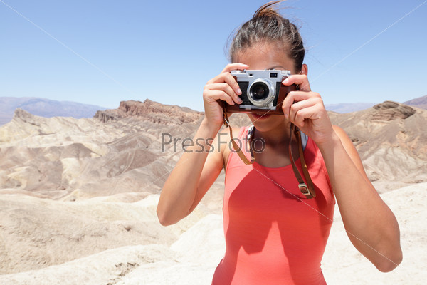 Tourist photographer woman taking pictures photo in Death Valley desert landscape of Zabriskie Point in Death Valley National Park, California, USA. Young woman on travel in United States.