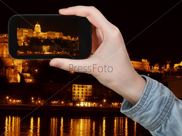 travel concept - tourist taking photo of Hungarian Parliament Building in night on mobile gadget, Hungary