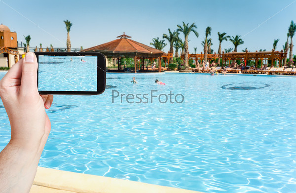 travel concept - tourist taking photo of children swimming in pool on mobile gadget, Egypt