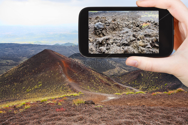 travel concept - tourist taking photo of craters volcano Etna on mobile gadget, Sicily, Italy