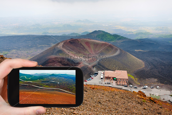 travel concept - tourist taking photo of station Rifugio Sapienza on Etna on mobile gadget, Sicily, Italy
