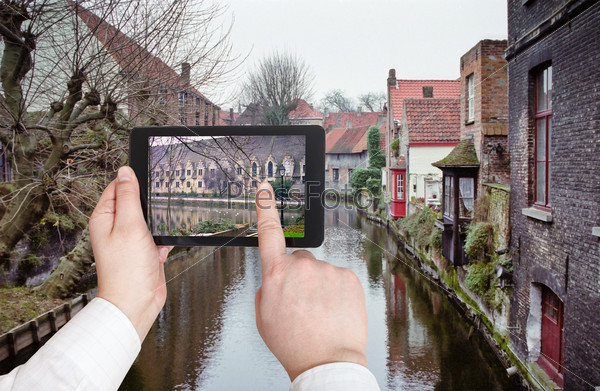 travel concept - tourist taking photo of canal in Bruges on mobile gadget, Belgium