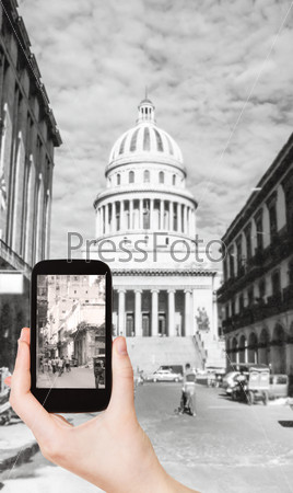 travel concept - tourist taking photo of El Capitolio, or National Capitol Building in Havana, Cuba on mobile gadget