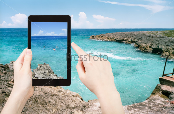 travel concept - tourist taking photo of stone coastline of Caribbean Sea in Bay of Pigs of on mobile gadget, Cuba