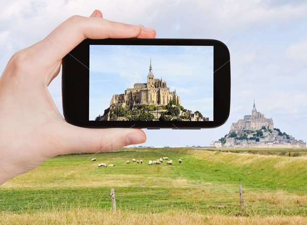 travel concept - tourist take photo of mont saint-michel abbey, Normandy, France on mobile gadget