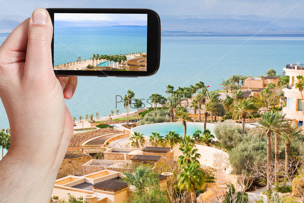 travel concept - tourist taking photo of Dead Sea in Jordan on mobile gadget