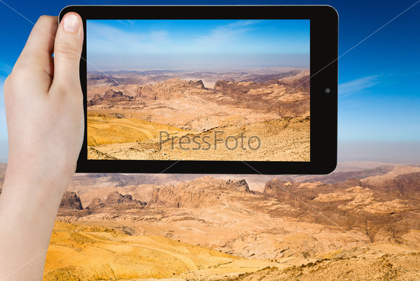 travel concept - tourist taking photo of mountain panorama of Jordan near Petra on mobile gadget