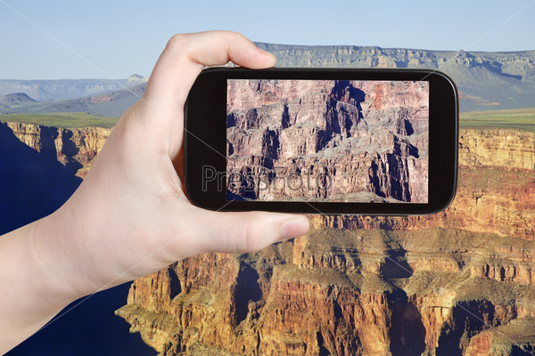 travel concept - tourist taking photo of rocky mountains in Grand Canyon on mobile gadget, Nevada, USA