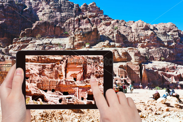 travel concept - tourist taking photo of tombs and houses in stone city Petra, Jordan on mobile gadget
