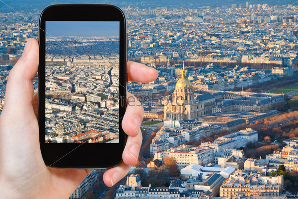 travel concept - tourist taking photo of Paris panorama at sunset on mobile gadget