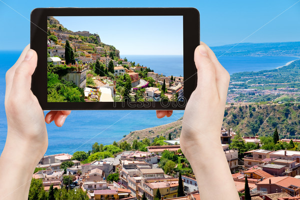 Travel concept - tourist taking photo town Taormina from Castelmola, Sicily, Italy of on mobile gadget, stock photo