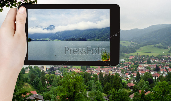 Travel concept - tourist taking photo of Schliersee town - climatic health resort in Bavarian Alps on mobile gadget, Germany, stock photo