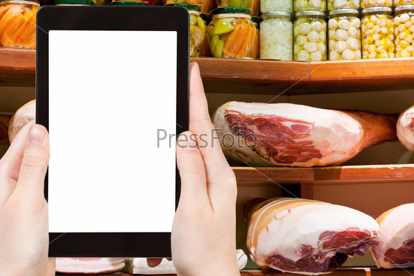 Travel concept - tourist photograph hams and salty bacon in small local shop in Bologna, Italy on tablet pc with cut out screen with blank place for advertising logo, stock photo