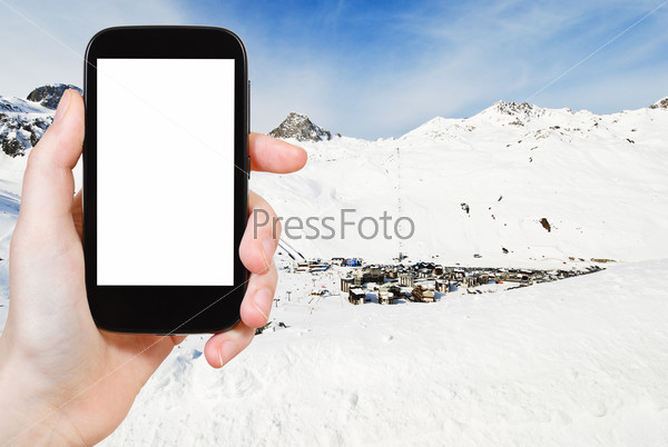 travel concept - tourist photograph view of town Tighnes between snow mountains in Paradiski region, Val d Isere - Tignes, France on tablet pc with cut out screen with blank place for advertising logo