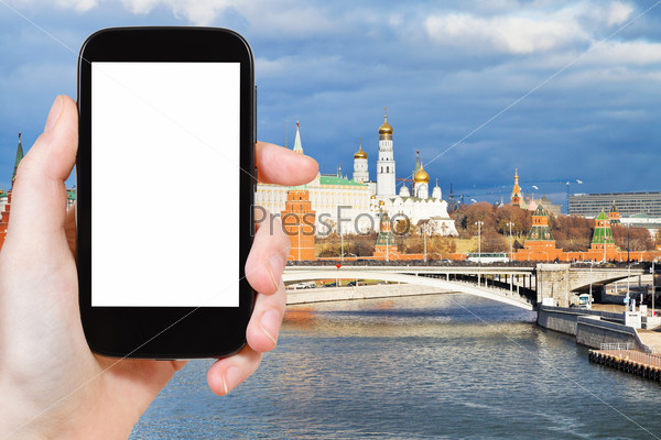 travel concept - tourist photograph Bolshoy Kamenny bridge, Moskva River and Moscow Kremlin in autumn day on smartphone with cut out screen with blank place for advertising logo