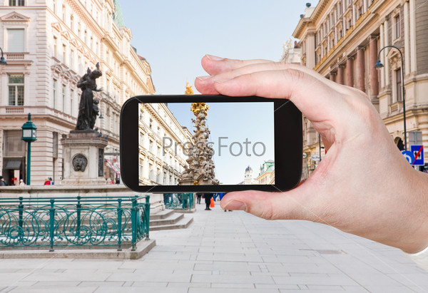travel concept - tourist taking photo of plague column on Graben, main historical street in Vienna, Austria on mobile gadget