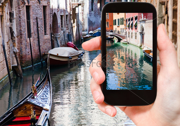 travel concept - tourist taking photo of canal, gondola, boats in Venice, Italy on mobile gadget