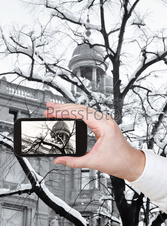 travel concept - tourist taking photo of snow on bare tree in Zurich city on mobile gadget Switzerland