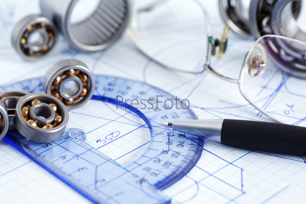 Industrial concept. Few ball bearings near ruler and spectacles on graph paper background
