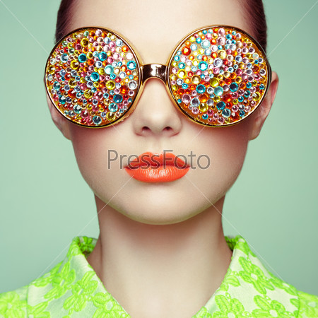Portrait of beautiful young woman with colored glasses. Beauty fashion. Perfect make-up. Colorful decoration. Jewelry