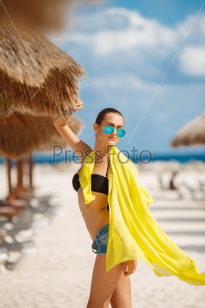 Beautiful sexy woman relaxing on the beach - outdoors. Young tanned woman on the beach in bikini and sunglasses. Young pretty hot sexy woman on the tropic island in summer near the sea